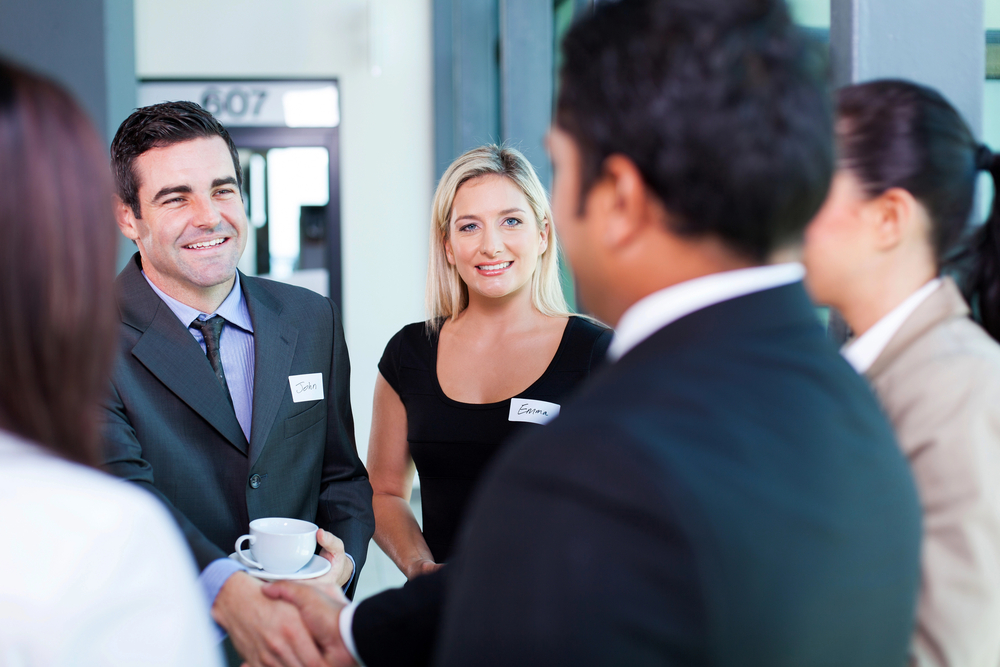 alt= business people making small talk with each other and shaking hands at a networking event 